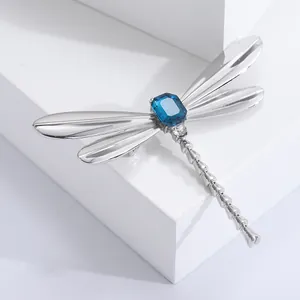 Vintage dragonfly brooch with dark blue gemstone and silver wings on white display