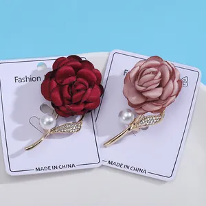 Elegant rose flower brooches with pearls and rhinestones on light blue background