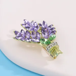 Détail de la broche lavande avec cristaux violets et tiges dorées sur support blanc