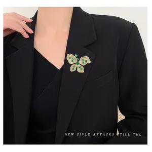 Élégante broche papillon avec pierres vertes et cristaux sur un revers de costume noir