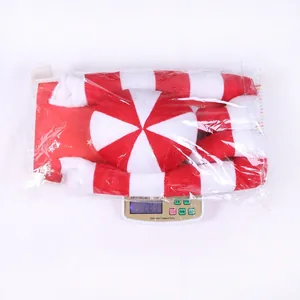 Close-up of a striped Christmas plush decoration being weighed on a scale in a warehouse