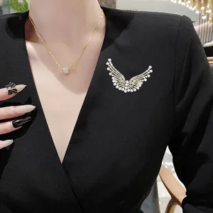 Élégante broche en alliage doré en forme d'aile avec strass étincelants sur vêtement noir
