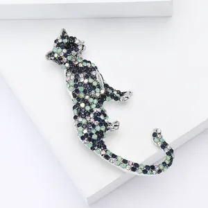 Detailed close-up of a silver-toned leopard brooch featuring blue and green rhinestones