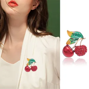 Charmante broche cerise en émail avec strass rouges et feuilles vertes sur costume