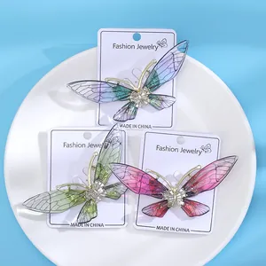 Drei elegante Schmetterlingsbroschen aus Acryl in Blau, Grün und Rosa auf weißem Tablett