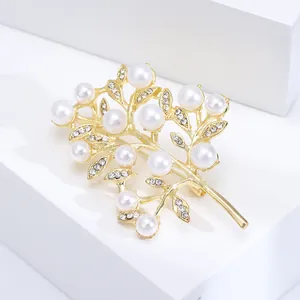 Broche arbre en métal doré avec perles blanches et strass brillants sur socle blanc chic