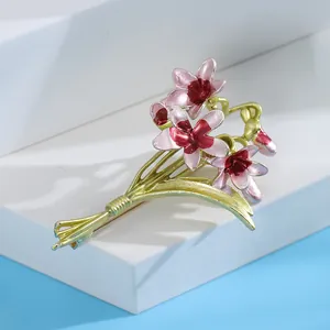 Elegant pink enamel orchid flower brooch with green leaves on white display stand