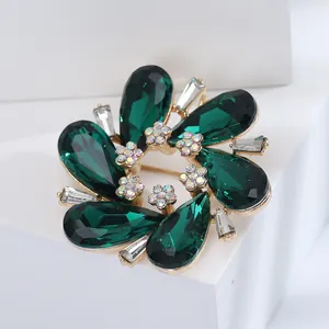 Elegant floral crystal brooch with emerald green teardrop stones and golden metal base