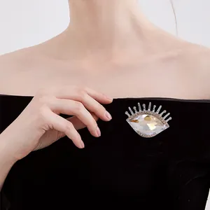 Broche œil de luxe élégante avec pierre précieuse champagne sur robe noire