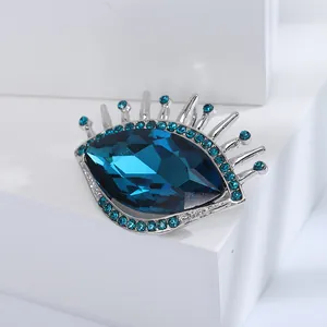Broche œil élégante avec cristal bleu foncé et monture argentée sur pierre blanche