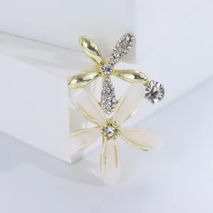 Elegante goldene Blumenbrosche mit weißen Blütenblättern und Kristallen auf weißem Grund