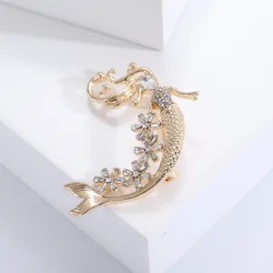 Elegante spilla a sirena dorata con fiori di strass su supporto bianco moderno