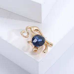 Detailansicht einer goldenen Katzenbrosche mit einem großen tiefblauen Kristallstein