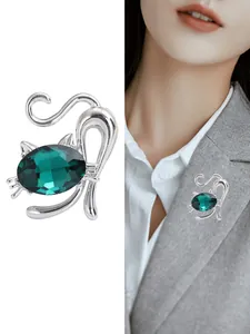 Detailansicht der silbernen Katzenbrosche mit grünem Kristall auf einem Blazer Revers