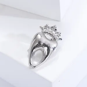 Detailed view of silver crown tooth brooch with rhinestones on a white geometric stand