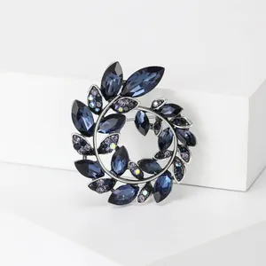 Detailaufnahme der Olivenzweig-Brosche mit tiefblauen Kristallen im Marquise-Schliff