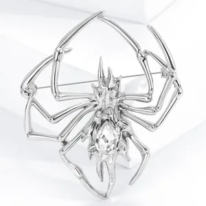 Detail of creative silver spider brooch featuring a large teardrop crystal on geometric blocks