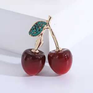 Macro d'une broche cerise rouge avec tige dorée et feuilles serties de cristaux verts