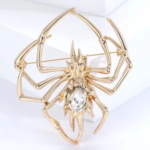 Macro detail of a golden spider brooch with a water drop crystal on a white stand