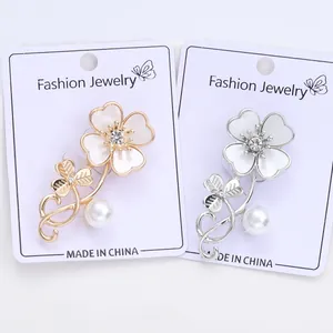 Detail of elegant four-leaf clover flower brooches in gold and silver with white shell petals
