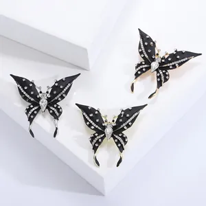 Fashion butterfly brooches with black enamel and rhinestones on white geometric stands