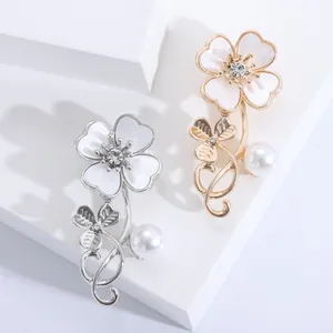 Macro detail showing gold and silver floral shell brooches with pearls and crystals