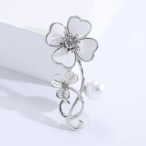 Detail of elegant silver clover brooch with white enamel petals and a central rhinestone