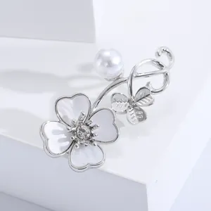 Detail of flower brooch with white shell petals, pearl accents and zircon inlay