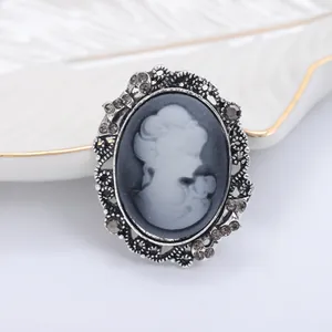 Close-up of vintage cameo brooch with lady profile, grey rhinestones, and silver alloy