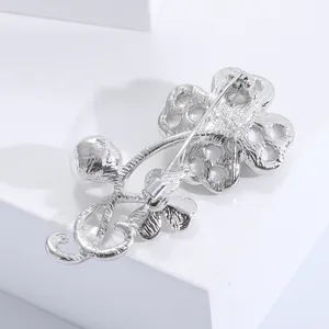 Detail showing the silver metal hollow-out structure and safety pin clasp on the brooch back