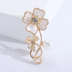 Macro detail of elegant flower brooch with shell petals, crystal center and a pearl drop