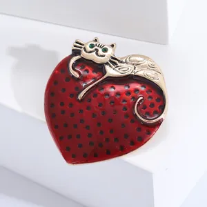 Cartoon cat on red heart enamel brooch with green gemstone eyes on white stand