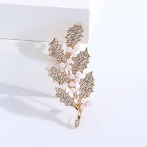 Élégante broche en forme de feuille dorée avec cristaux et perles sur décor blanc