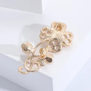 Macro view of the gold clover brooch back showing refined matte texture and pin clasp