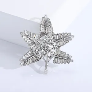 Macro detail of leaf brooch featuring silver metal, round rhinestones, and rectangle crystals