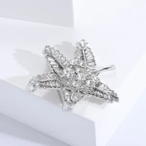 Macro shot of silver baroque snowflake brooch featuring sparkling crystals on white props