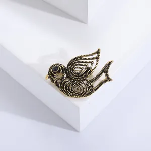 Broche oiseau vintage en bronze antique avec œil en pierre noire sur socle blanc