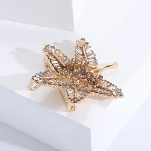 Detail view of baroque gold leaf brooch with champagne crystals on a white pedestal