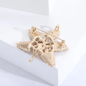 Detail of golden maple leaf brooch featuring a dual-purpose pin and pendant loop