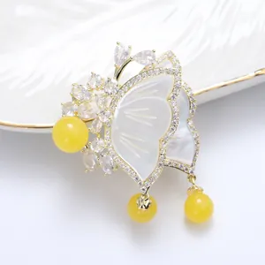 Elegant butterfly brooch with white mother-of-pearl wings and yellow beads on ceramic plate