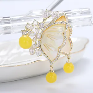 Detailed macro view of 3D butterfly brooch with pearl shell wings and golden finish