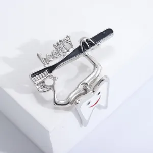 Close-up of a dentist theme brooch featuring a smiley tooth, toothbrush and healthy text