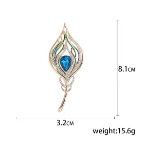 Golden feather brooch with blue gemstone and green enamel, size 8.1cm by 3.2cm