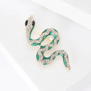 Broche serpent élégante en émail vert avec strass brillants sur un support blanc minimaliste