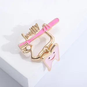 Close-up of gold and pink toothbrush brooch with a smiling tooth and healthy text