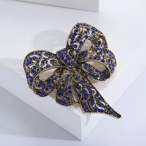 Dettaglio della spilla a fiocco vintage con strass blu scuro e finitura in oro anticato