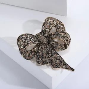Dettaglio spilla a fiocco in oro vintage con strass su un supporto bianco puro