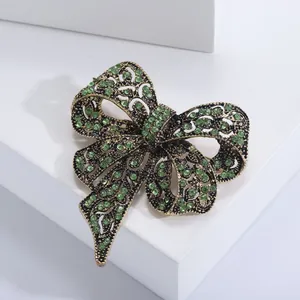 Dettaglio ravvicinato di una spilla a fiocco vintage con strass verdi e finitura dorata