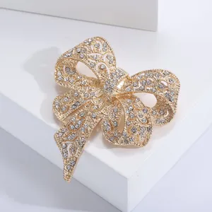 Macro della spilla a fiocco dorata con intaglio vuoto e dettagli in strass bianchi