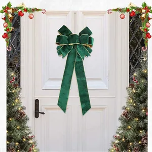 Large dark green velvet Christmas bow with gold trim hanging on a white door